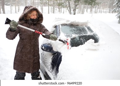 Woman Removing Snow From Car Windshield