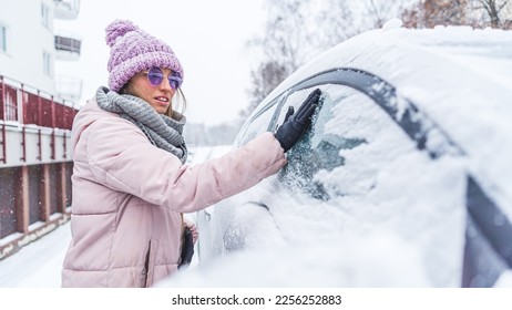 Woman removing the snow with her gloved hand off the car window . High quality photo - Shutterstock ID 2256252883
