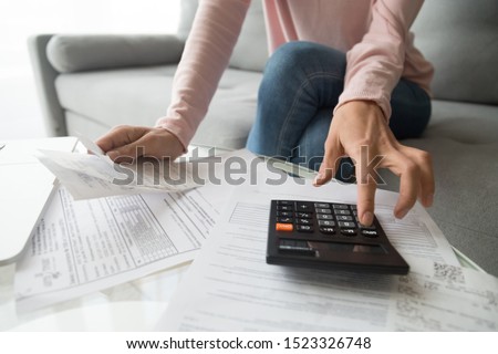 Woman renter holding paper bills using calculator for business financial accounting calculate money bank loan rent payments manage expenses finances taxes doing paperwork concept, close up view