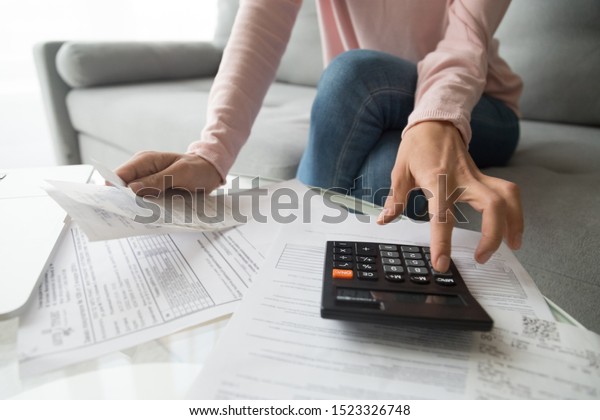 Woman renter holding paper bills using calculator\
for business financial accounting calculate money bank loan rent\
payments manage expenses finances taxes doing paperwork concept,\
close up view