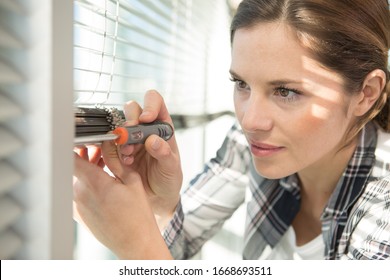 Woman Repairing A Window Blind With A Screwdriver