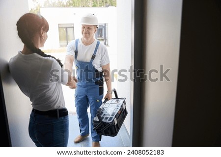 Woman and repairman handshaking in entrance to new townhouse before repair