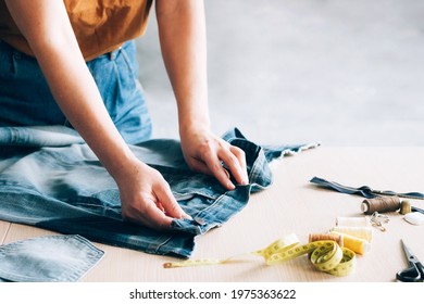 Woman repairs sews reuses fabric from old denim clothes economical reuse. DIY Hobby Reuse Recycling - Shutterstock ID 1975363622