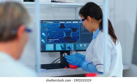 Woman research chemist testing virus sample in modern equipped laboratory. Multiethnic stuff examining vaccine evolution using high tech and technology researching treatment against covid19 virus - Shutterstock ID 1903155319