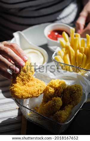 a woman in a restaurant or fast food cafe eats fried wings in air batter with different sauces and fries