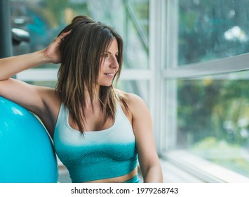 woman resting after a gym class. she is looking through a window very relaxed. concept happiness and physical well-being.