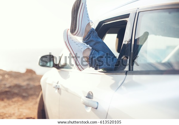woman\
resting in the car with sneakers out of the\
window