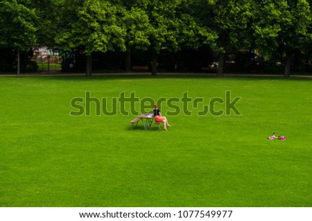  woman resting in a city park in summer against a background of a green field 
