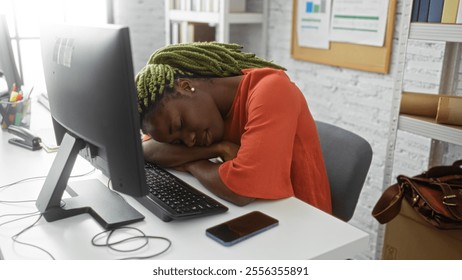 Woman resting at desk inside office with head on arms wearing orange shirt beside computer, phone on desk emphasizes workplace fatigue and relaxation, young adult setting. - Powered by Shutterstock