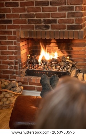 Woman resting in front of the fire of a fireplace in winter comfortably.