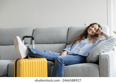 Woman resting in the living room of her house until it's time to go to the airport. Woman resting on the sofa waiting for her flight time. Woman on vacation has just arrived at the hotel.