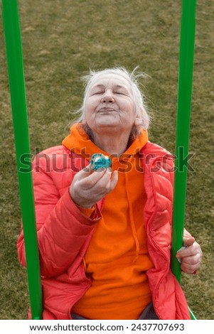 a woman of retirement age rides on a children's swing and eats a cake