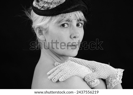 Woman in a retro hat looks into the camera and shows that she is expecting someone