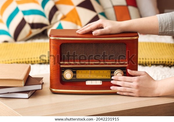 Woman with\
retro radio receiver on table in\
bedroom