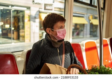 Woman Returning From The Farmers Market, Sitting In A Tram With Pink Coronavirus Face Mask Due To COVID-19 Pandemic