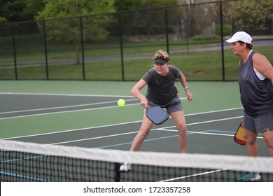 A Woman Returns A Pickleball Shot During A Women's Doubles Match