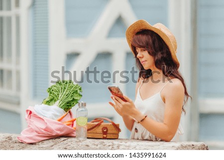 Woman with reusable water bottle  and  bamboo handbag, cotton grocery bag with vegetables. 