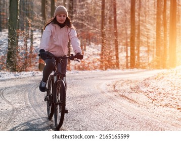 A Woman Rides A Bike In Winter. Concept Of Cycling During Snowy Weather. Snow And Sun Weather In The Park