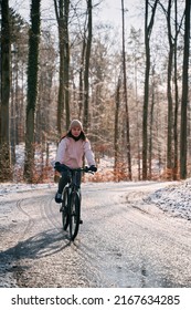 A Woman Rides A Bike In Winter. Concept Of Cycling During Snowy Weather. Snow And Sun Weather In The Park