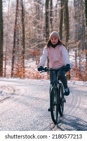 A Woman Rides A Bike In Winter. Concept Of Cycling During Snowy Weather. Snow And Sun Weather In The Park