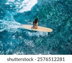 Woman rides on longboard on ocean wave. Drone view of woman during surfing