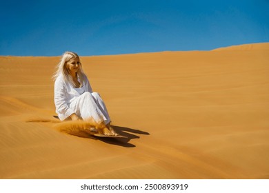 A woman rides a sandbox in the Rub Al Khali desert, Dubai. copyspace - Powered by Shutterstock