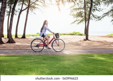 Woman Riding A Bicycle At The Beach. Smiling Young Model Posing While Riding Bike On The Road In Summertime.