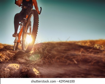 a woman riding a bicycle down a dirt trail with big rocks in the back country to get away from the city toned with a retro vintage instagram filter app or action effect 