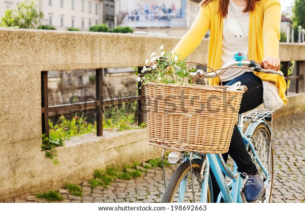 Woman riding bicycle with\
flowers 