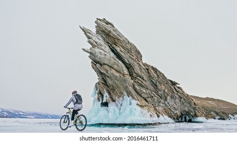 Woman is riding bicycle near the ice grotto. The rock with ice c - Powered by Shutterstock