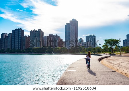 Woman Riding Bike Along Lake Michigan Towards the Sun in Chicago