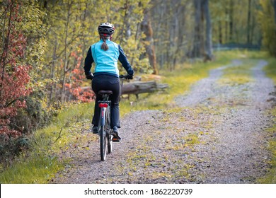 A woman riding a bike down a dirt road