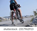 woman riding bike on gravel trail (young south asian, indian rider on bicycle trail) burlington vermont causeway path (brown skin, athletic clothes, cycling jersey, helmet)
