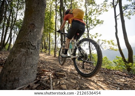 Woman riding bike on mountain top forest trail