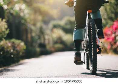 Mujer montando una bicicleta en el sendero de un parque tropical en primavera