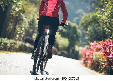 Woman riding a bike on tropical park trail in spring