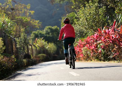 Woman riding a bike on tropical park trail in spring