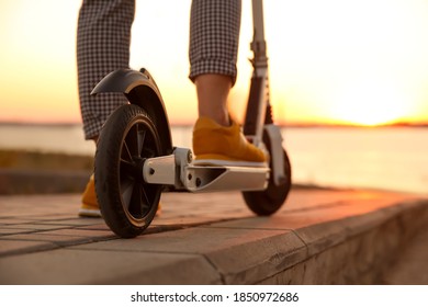 Woman riding electric kick scooter outdoors at sunset, closeup - Powered by Shutterstock