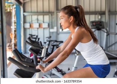 Woman Riding An Exercise Bike In Gym. Indoor Cycling Bicycle Wheels Spinning.