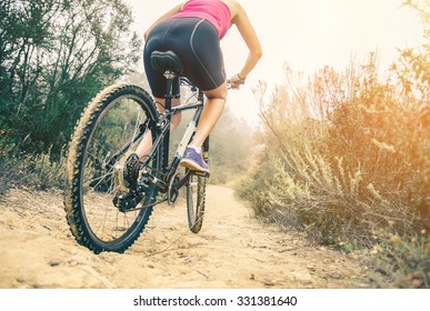 Woman Riding Her Mountain Bike On A Off Road Track - Athletic Girl Cycling In The Nature At Sunset, Close Up On Tire And Lower Body