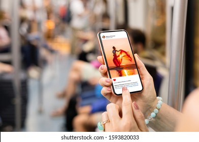 Woman riding in metro and viewing someone's photo on mobile phone.