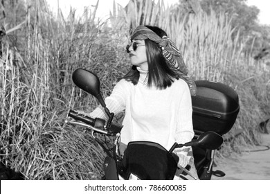The woman riding the motorcycle. She has a bandana and sunglasses.
