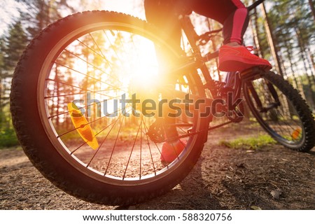 Woman riding a mountain bicycle along path at the forest. Closeup on pedal and foot. Healthy lifestyle and sport concept 
