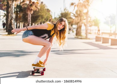 Woman riding a skateboard at the beach in california. Skater girl on a longboard. Cool female skateboarder at sunset.