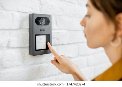 Woman Rings The House Intercom With A Camera Installed On The White Brick Wall