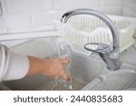 A woman rinses plastic bottles in the kitchen before sending them for plastic recycling. A woman sorts and washes household plastic waste for recycling. Zero waste, ecology.