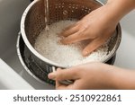 Woman rinsing rice in colander at sink, closeup