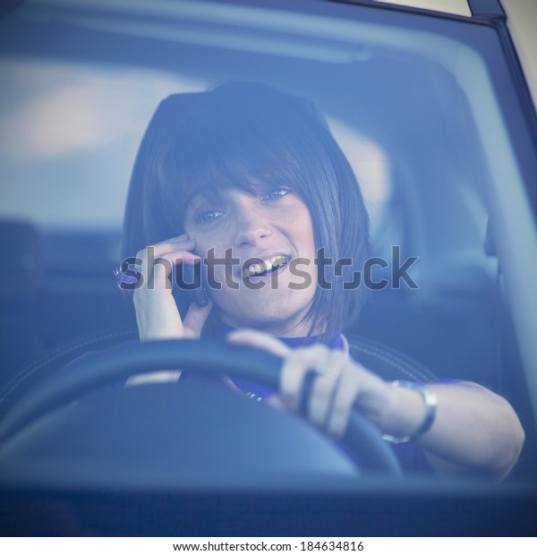 Woman in risk driving holding and talking at\
her cellphone