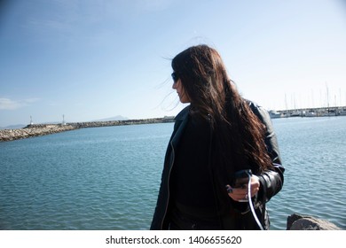 Woman Rocker Wearing Black Leather Jacket And Sunglasses With Fur Jacket Looking At The Horizon In The Sea Of Baja California Mexico