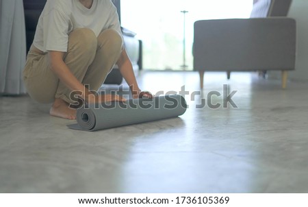 Woman roll out yoga mat on floor at home